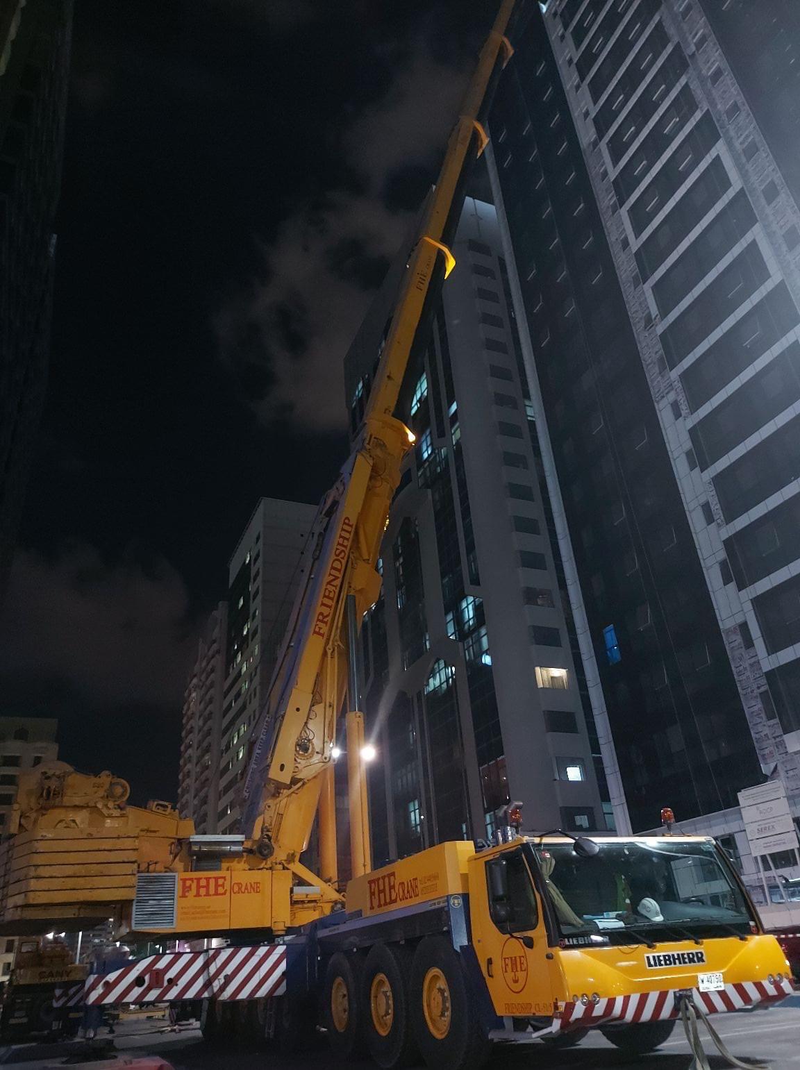 Large mobile crane working at a high-rise site at night